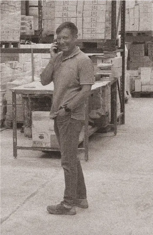 Miembro del equipo de Alma de Barro hablando por teléfono en el almacén de cerámica